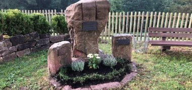 Gedenkstein mit Blumen und Bank