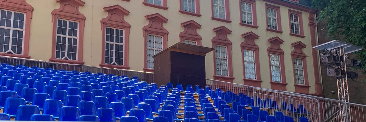 Blaue Sitze auf Tribünenelement vor Schloss