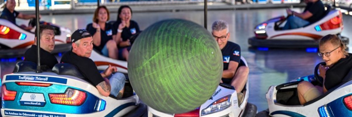 Scooter-Ball-Cup Menschen im Autoscooter fahren gegen einen Ball, der durch die Luft fliegt.