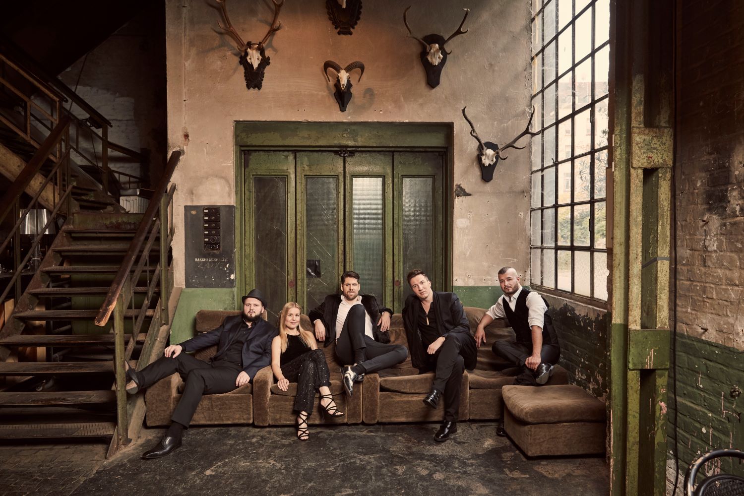 Fünf Musiker auf Sofa vor Wand mit Jagdtrophäen