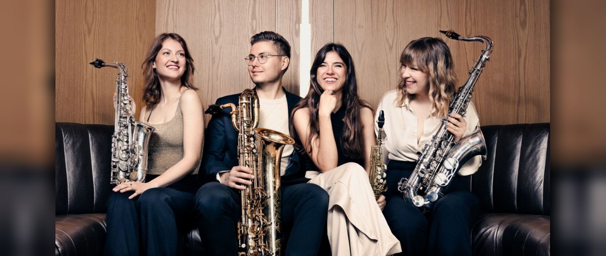 Eternum Quartet Vier Musiker - drei Frauen und ein Mann - sitzen auf einer Couch und halten ihre Blasinstrumente in der Hand.