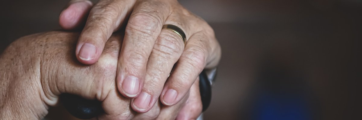 Hände eines Seniors, die sich auf Gehstock abstützen