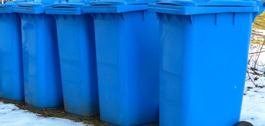 Blaue Papiermülltonnen nebeneinander im Schnee