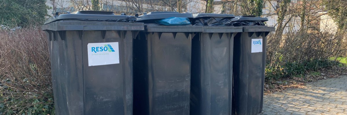 Vier gefüllte Mülltonnen am Straßenrand