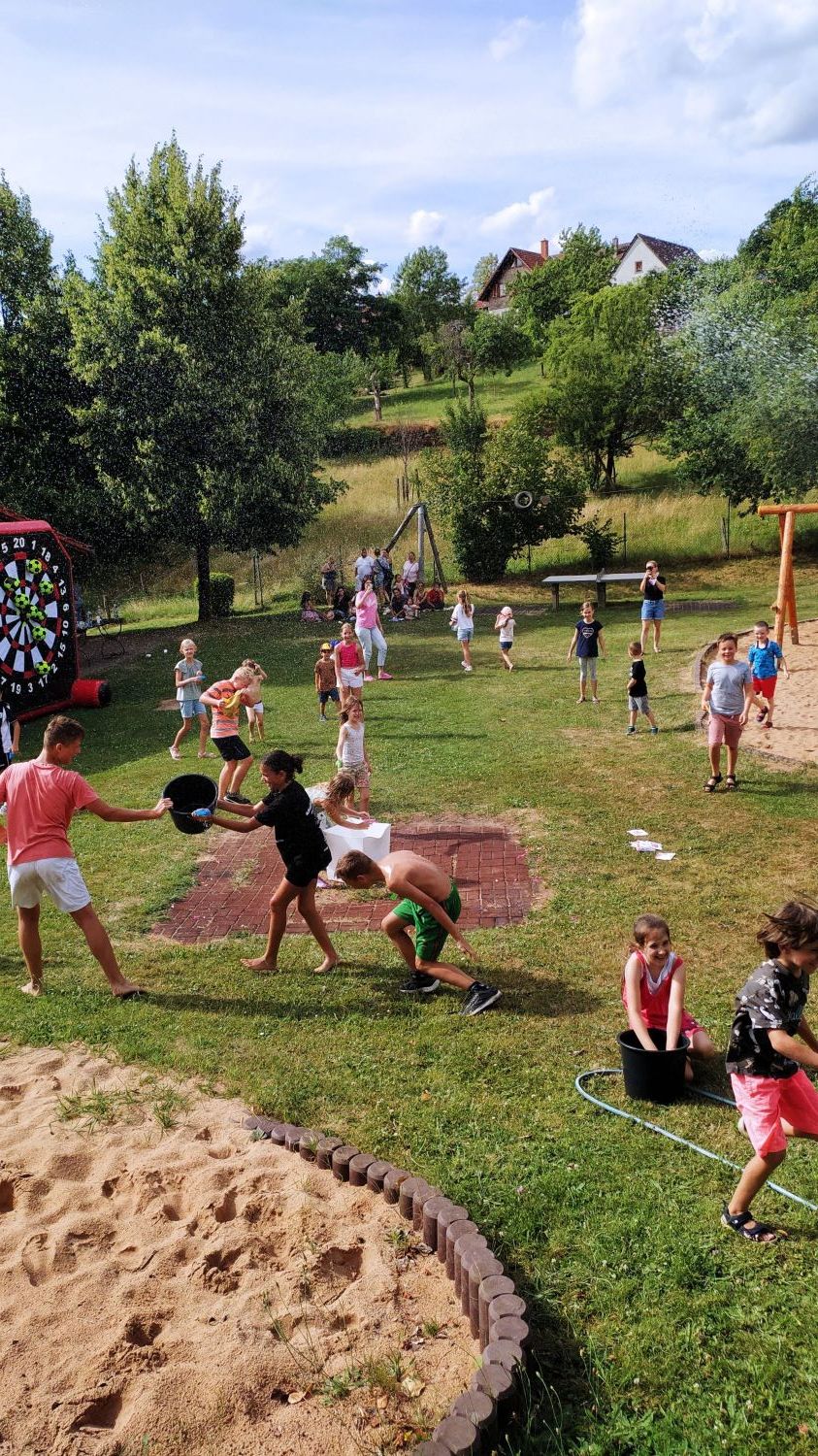 Kinder auf Wiese mit verschiedenen Spielgeräten