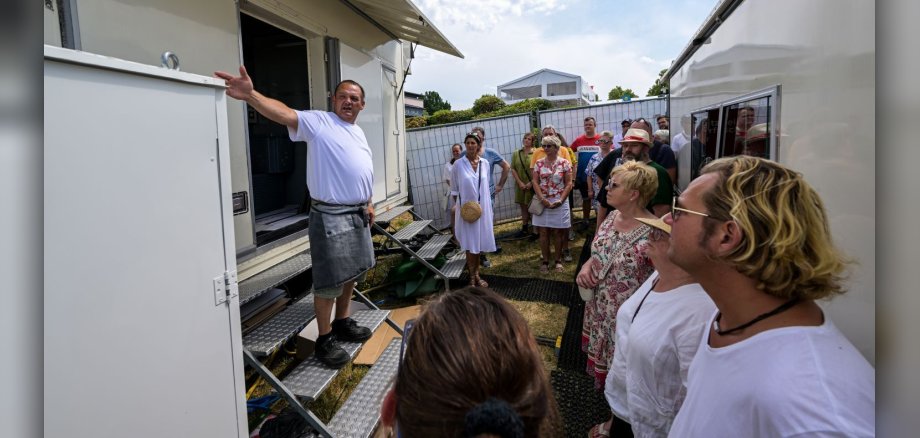 Backstage-Tour am Wiesenmarkt Marktbeschicker zeigt mehreren Personen Marktgelände
