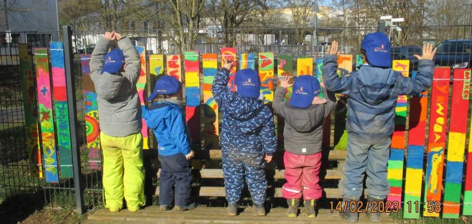 Neue Kappen für die Kita-Kunterbunt Kita-Kinder stehen mit dem Rücken zur Kamera und tragen blaue Kappen