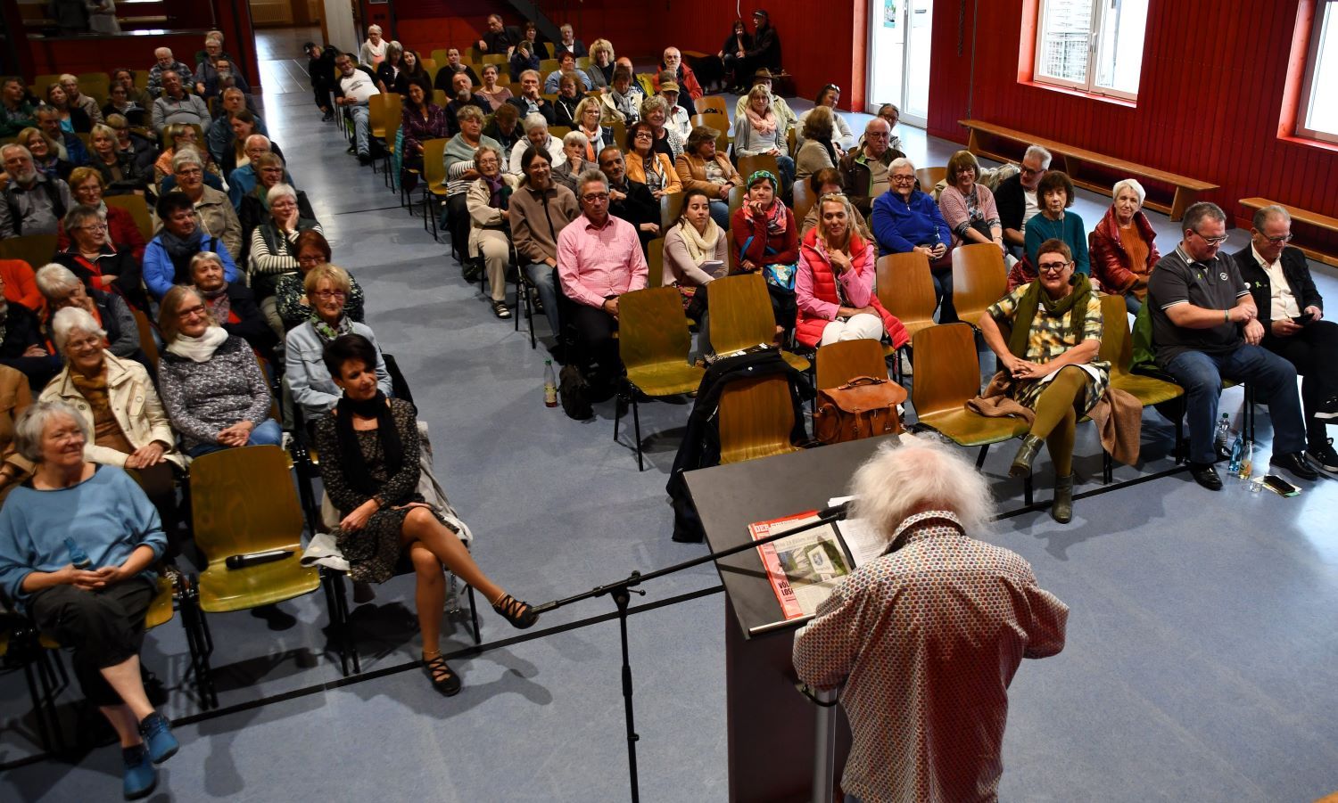Redner steht vor Personen und hält Vortrag