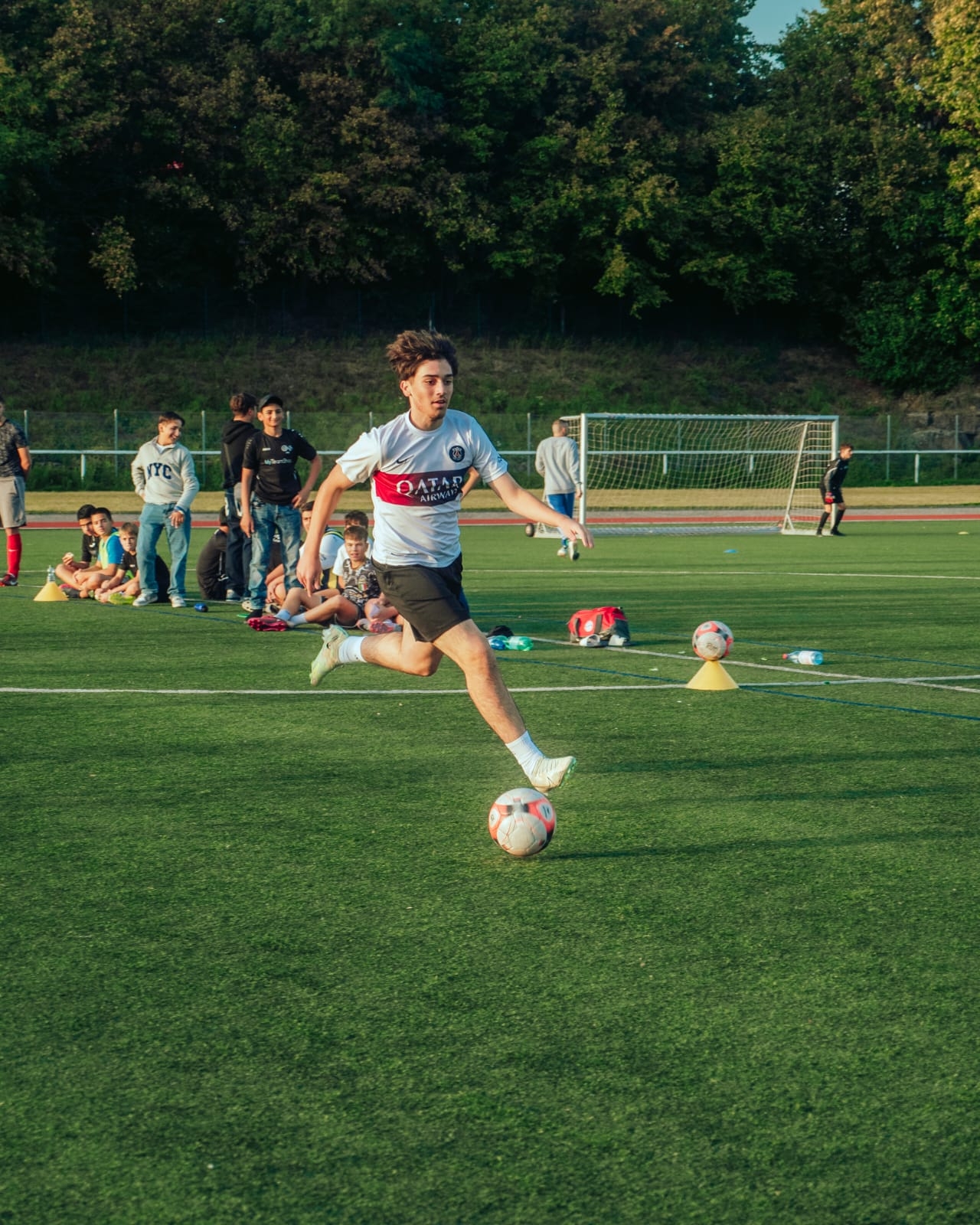 Jugendlicher lauft auf Ball auf Fußballplatz zu