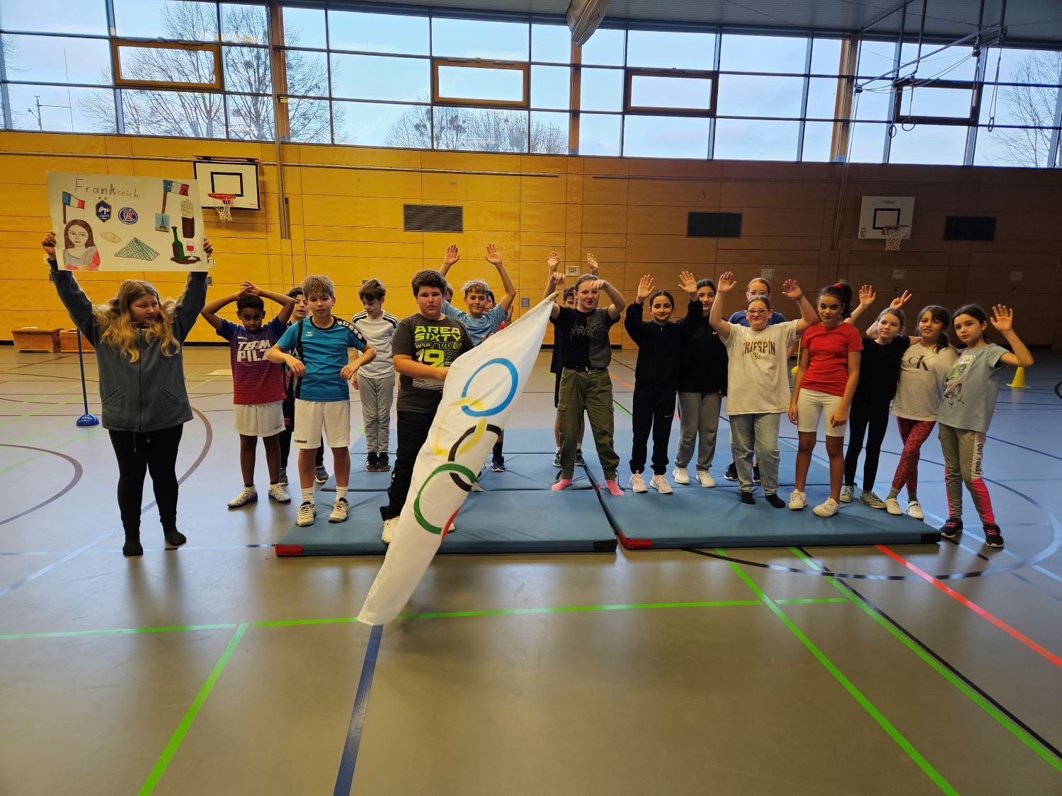 Kinder posieren für Gruppenbild mit Olympia-Flagge