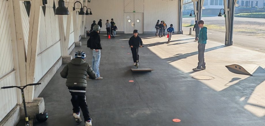 Kinder in Sportanlage, die auf Scootern fahren