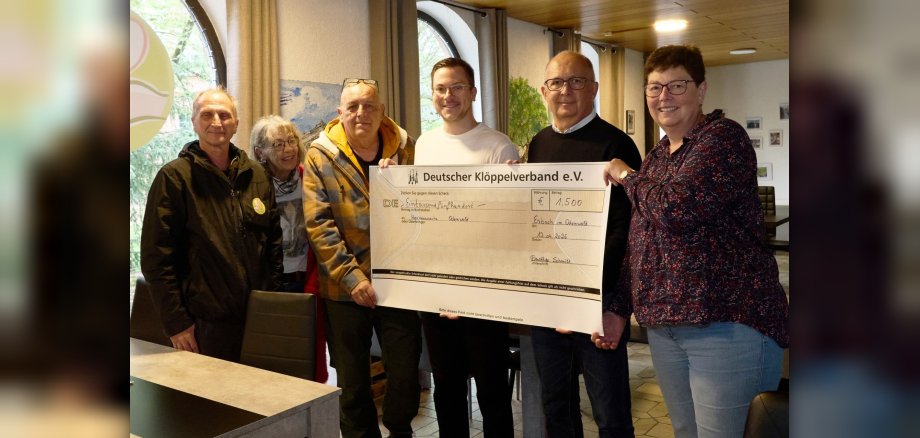 Vier Männer und drei Frauen halten einen großen Spendenscheck bei einer Übergabe fest