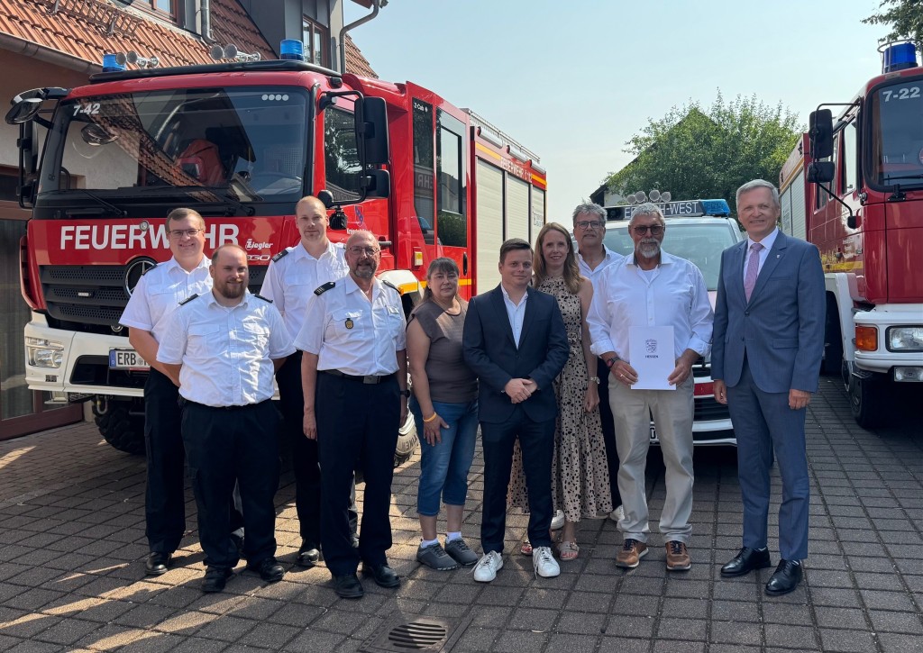 Gruppenbild mit vielen Menschen vor Feuerwehrfahrzeugen.
