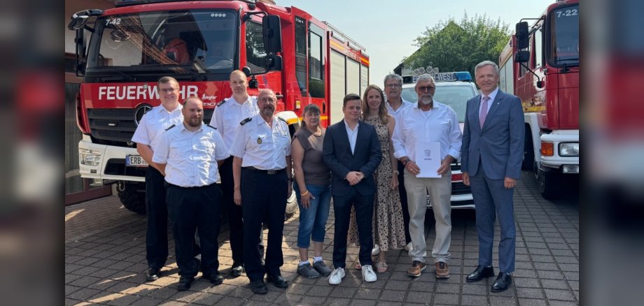 Gruppenbild mit vielen Menschen vor Feuerwehrfahrzeugen.