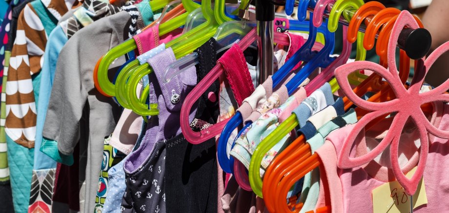 Kinderkleidung auf Kleiderbügeln bei einem Flohmarkt