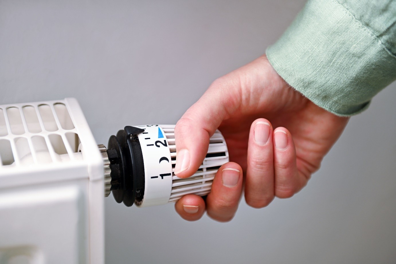 Hand, die an Heizungsregler dreht