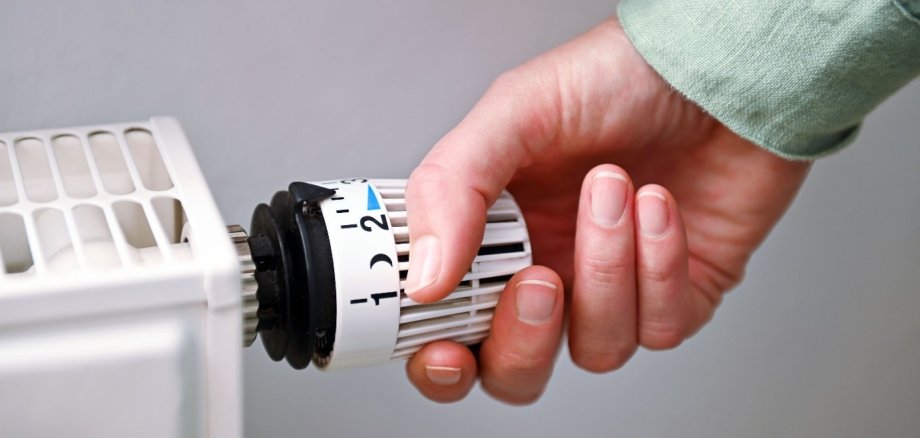 Hand, die an Heizungsregler dreht