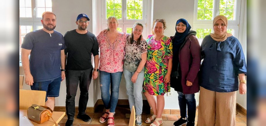 Gruppenbild mit zwei Männern und fünf Frauen, die alle in die Kamera lächeln