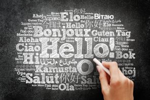 Verschiedene Sprachen Schreibtafel, auf die eine Hand mit Kreide Hallo in vielen verschiedenen Sprachen schreibt