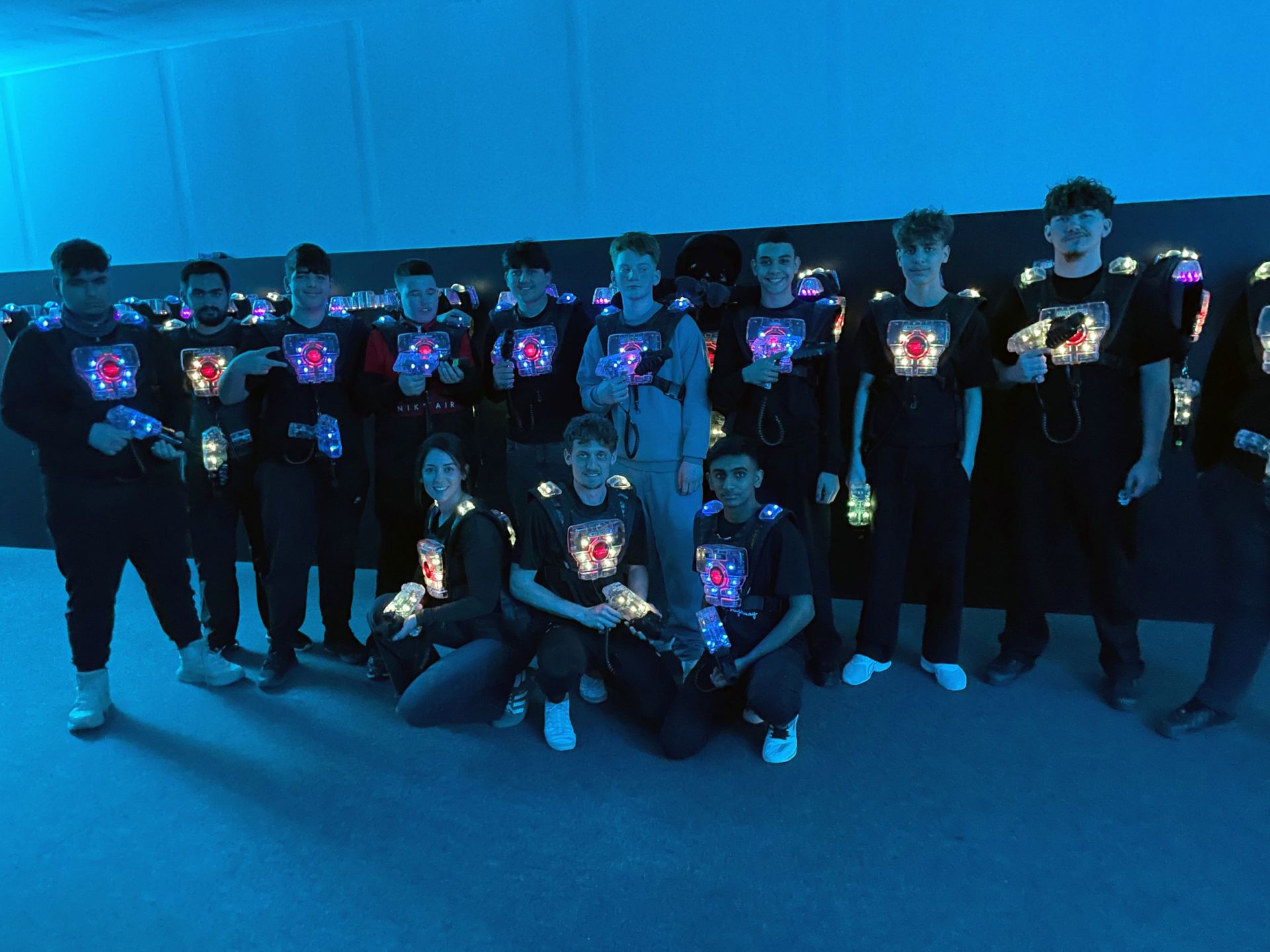 Jugendliche in dunkler Halle mit Lasertag-Kleidung