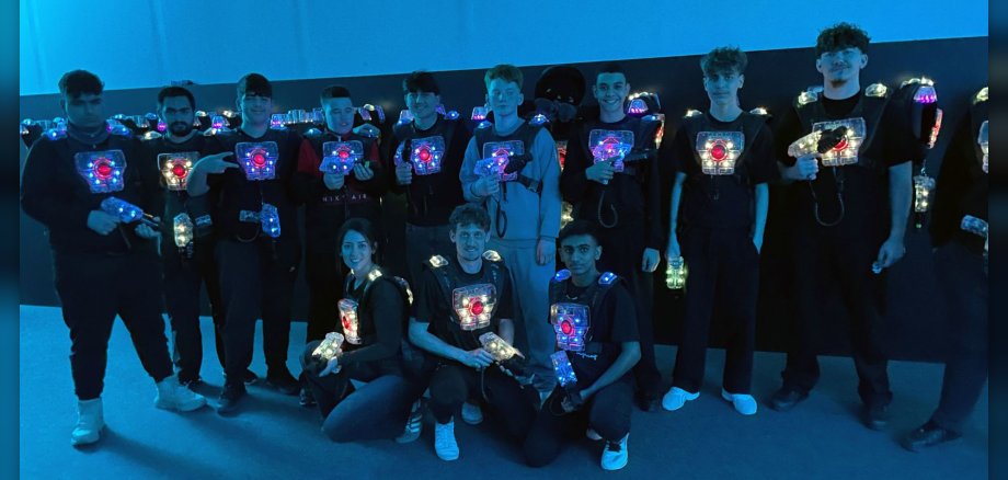 Jugendliche in dunkler Halle mit Lasertag-Kleidung