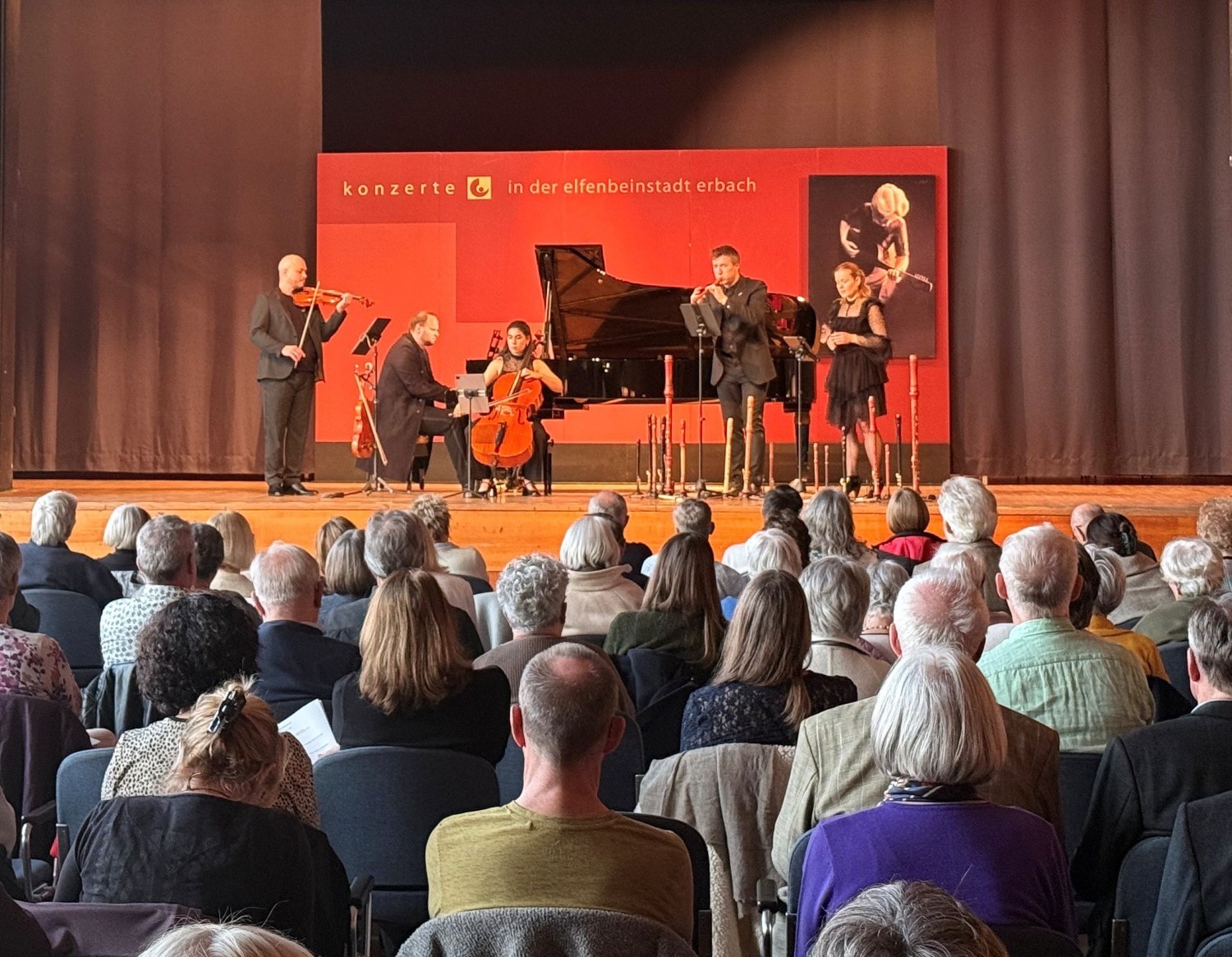 Musikerinnen und Musiker auf einer Bühne vor Publikum