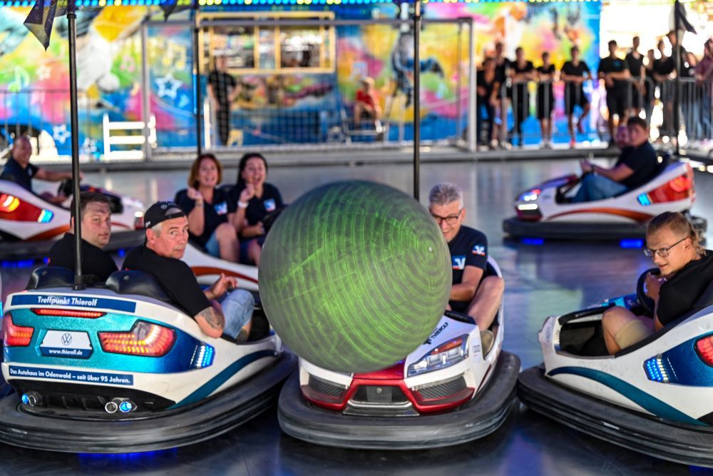 Menschen im Autoscooter fahren gegen einen Ball, der durch die Luft fliegt.