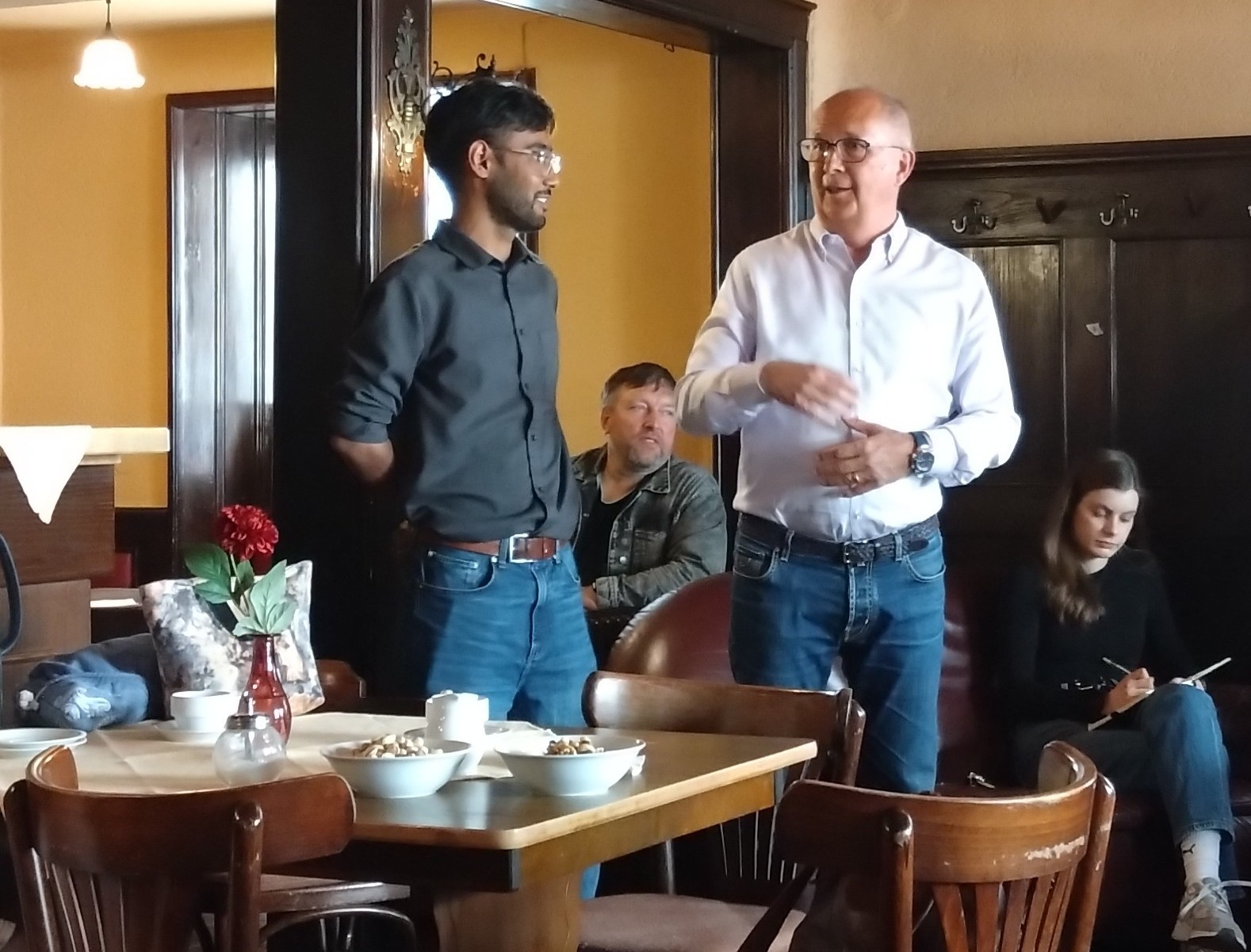 Zwei Männer halten eine Rede in den Räumlichkeiten eines Cafés