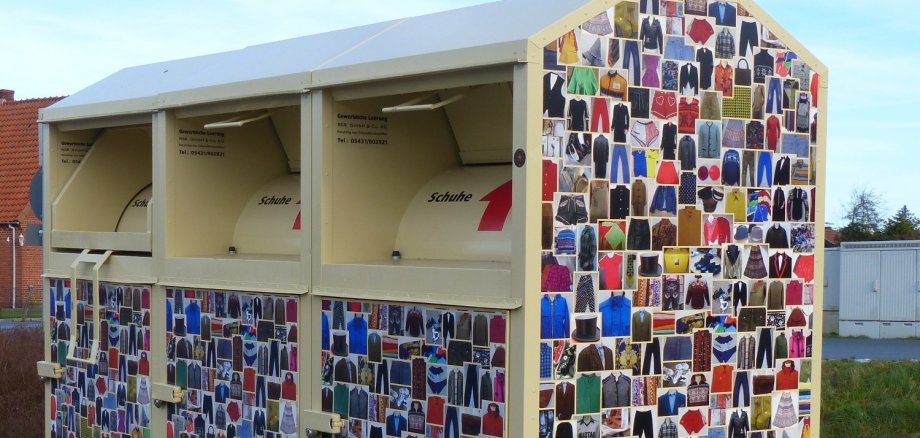 Drei Altkleidercontainer nebeneinander. Auf den Seiten sind Bilder von Kleidung aufgeklebt.