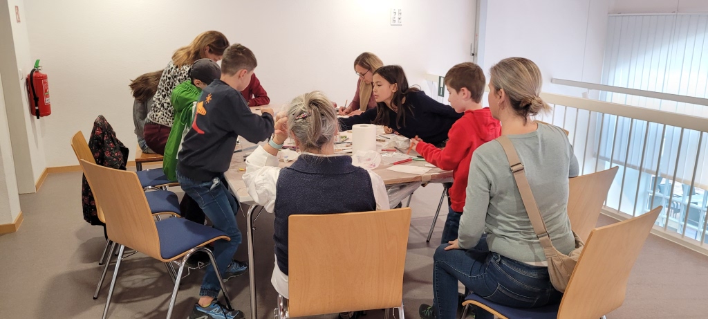 Kinder sitzen an einem Tisch und basteln.