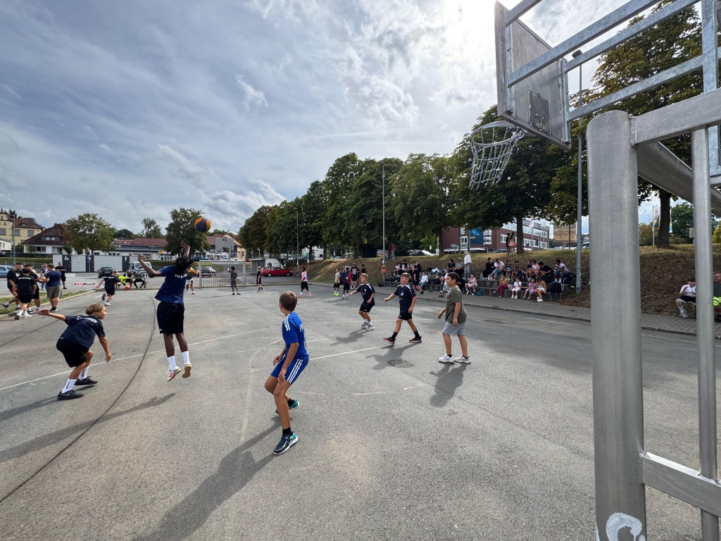 Kinder spielen Basketball auf einem asphaltierten Basketballplatz