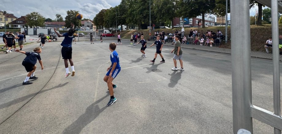 Kinder spielen Basketball auf einem asphaltierten Basketballplatz