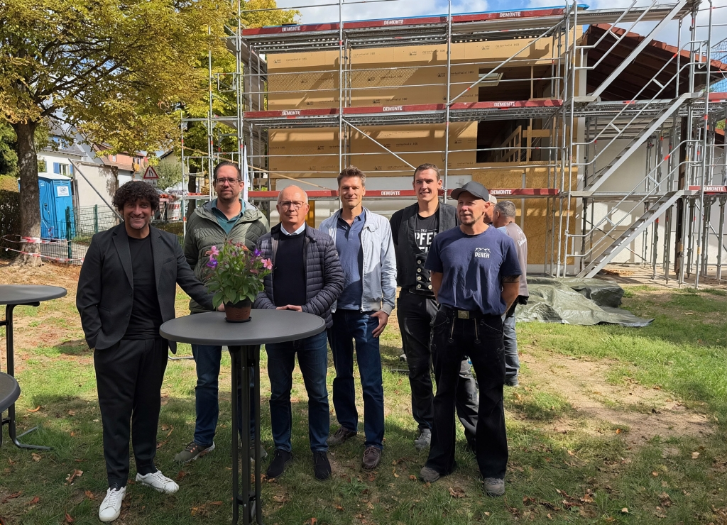 Gruppenbild von sechs Männern vor einem Kindergarten mit Baustelle