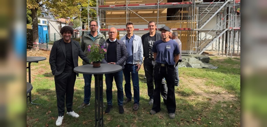 Richtfest Kindergarten Sonnenschein Gruppenbild von sechs Männern vor einem Kindergarten mit Baustelle