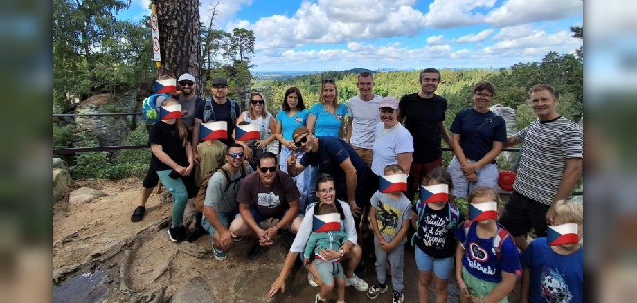 Gruppenbild Reunion-Treffen in Jicin Gruppenbild einer Gruppe von Männern und Frauen mit Kindern in einer Waldlandschaft. Die Kinder wurden unkenntlich gemacht.