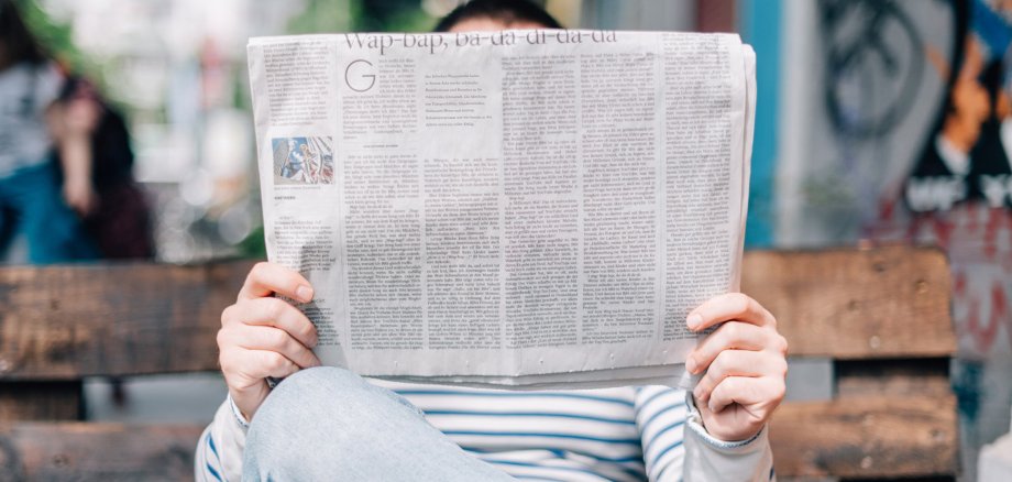 Mann auf Parkbank mit Zeitung in der Hand