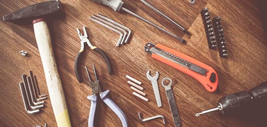 Hammer, Schraubenzieher und verschiedene Zangen auf Tisch verteilt