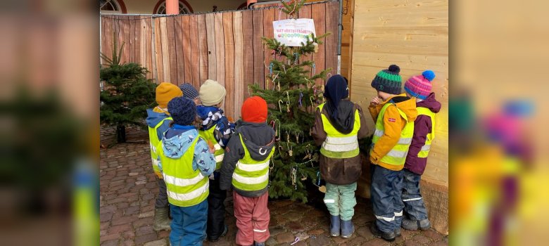 Kita-Kinder stehen vor Weihnachtsbaum auf Marktplatz
