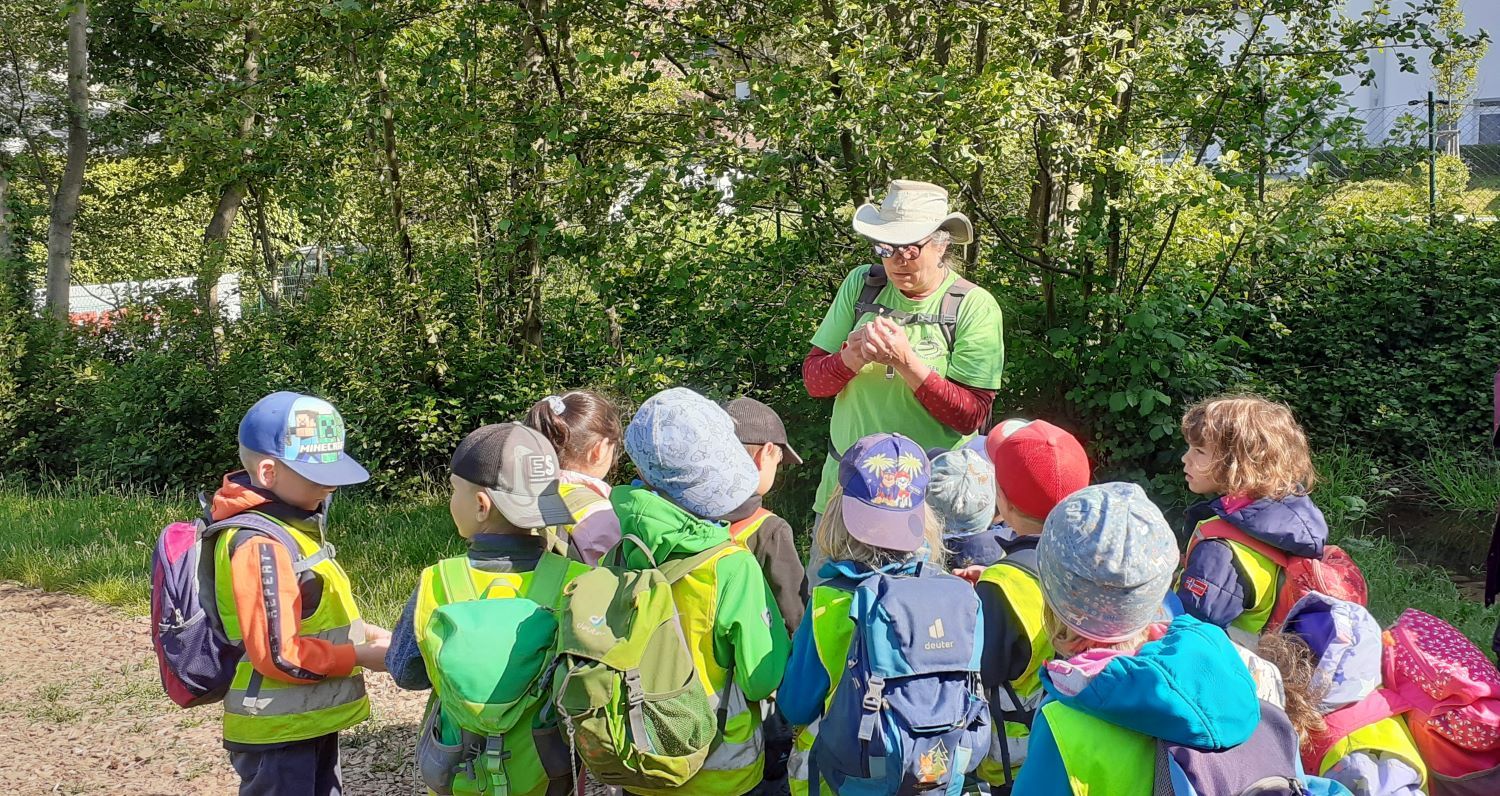 Frau udn Kita-Kinder am Wiesenrand