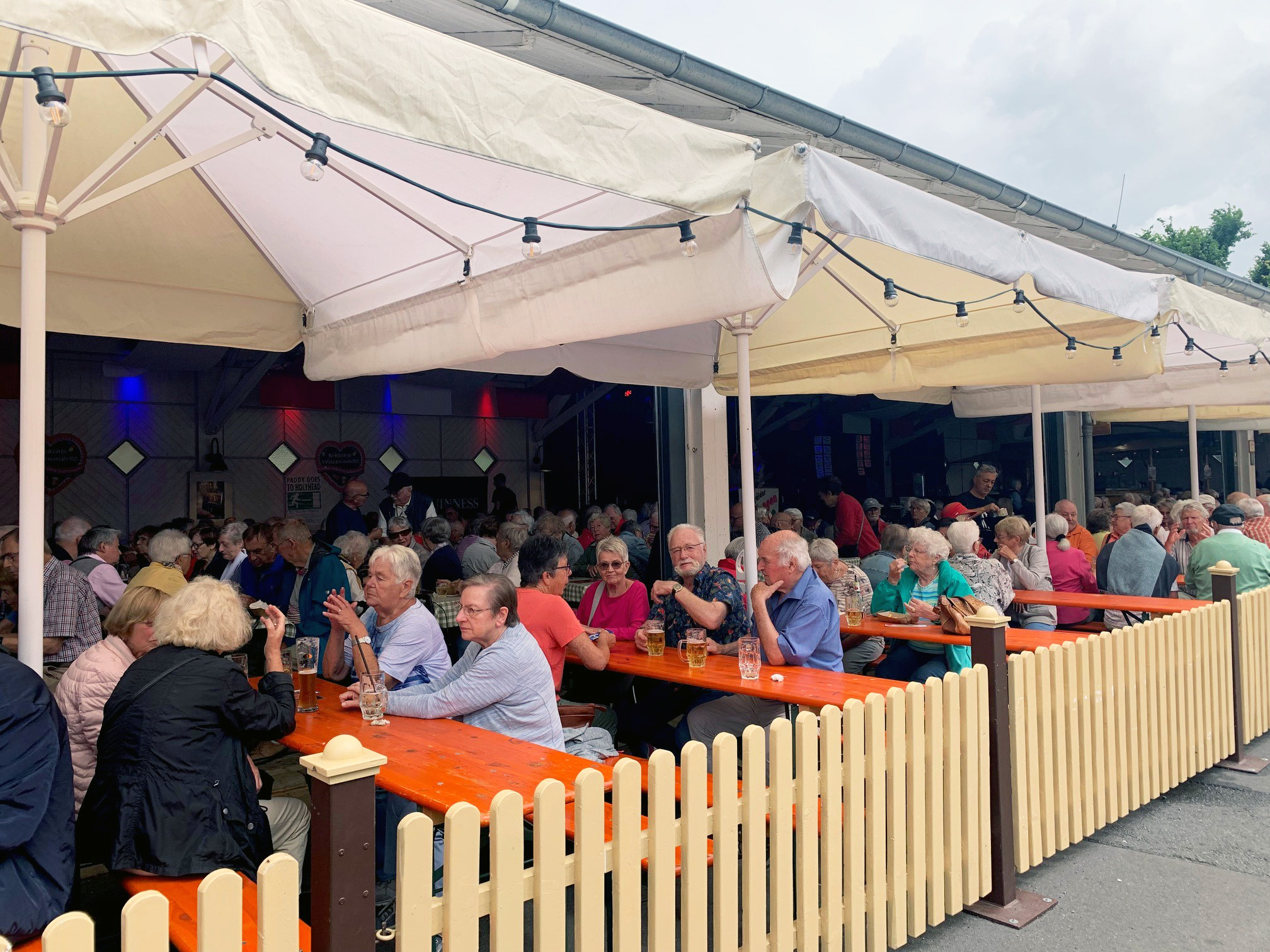 Senioren auf Bierbankgarnituren in Festhalle