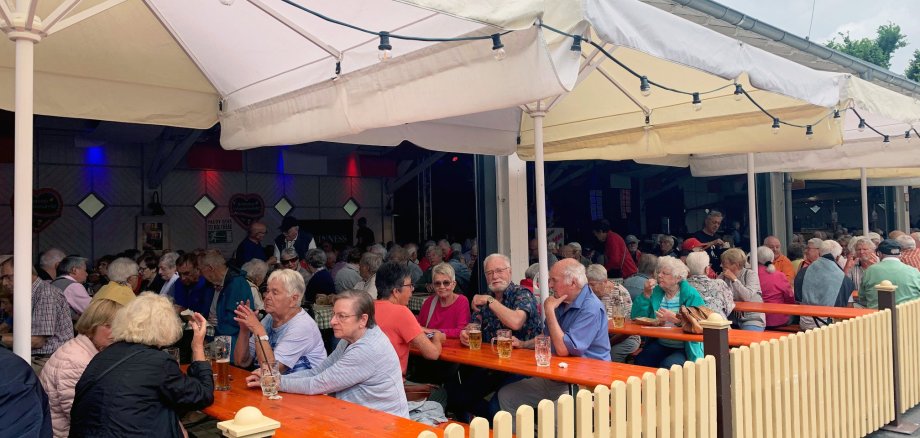 Senioren auf Bierbankgarnituren in Festhalle