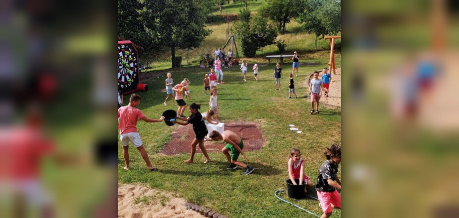 Kinder auf Wiese mit verschiedenen Spielgeräten