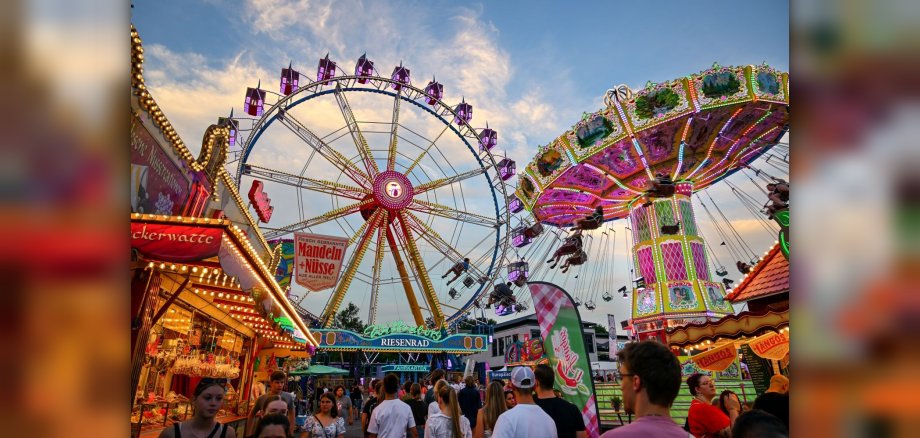 Riesenrad und Kettenflieger mit Menschen im Vordergrund