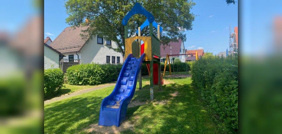 Rutschturm auf Spielplatz mit Haus im Hintergrund