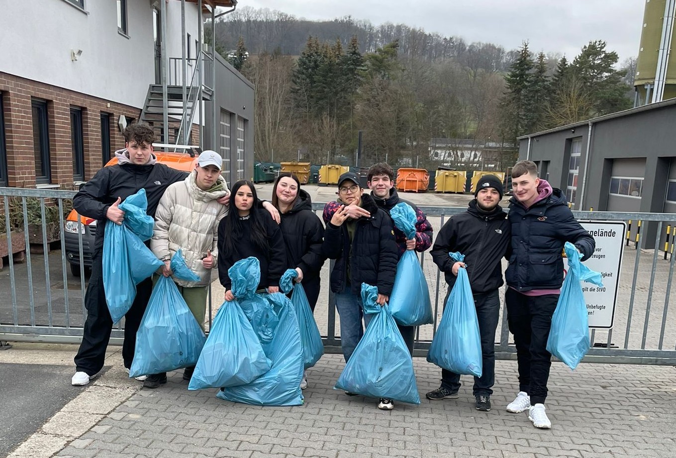 Jugendliche halten blaue Müllsäcke, die sie zuvor mit gesammeltem Müll gefüllt haben