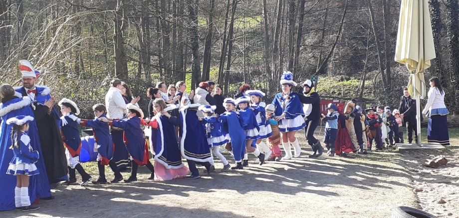 Fastnachter und verkleidete Kinder machen Polonaise durch Kindergartengelände