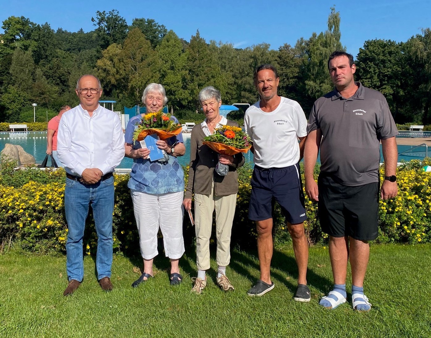Gruppenbild von drei Männern und zwei Frauen mit Blumensträußen
