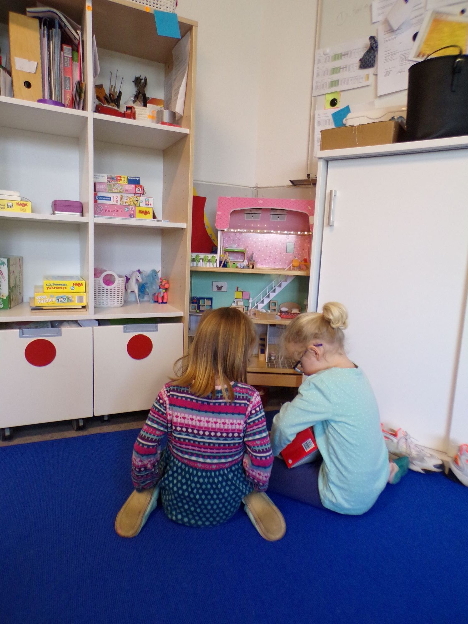 Zwei kleine Mädchen spielen mit Puppenhaus