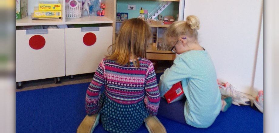 Zwei kleine Mädchen spielen mit Puppenhaus