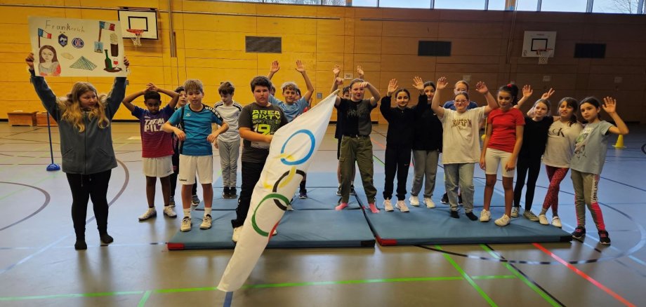 Kinder posieren für Gruppenbild mit Olympia-Flagge